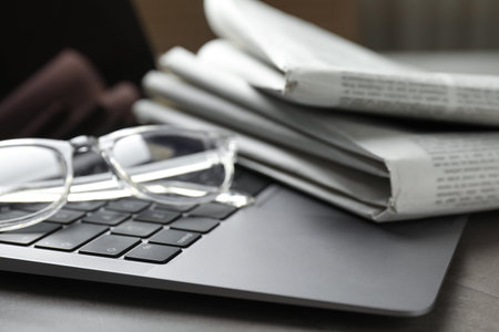 Newspapers, laptop and glasses on gray table, closeupの写真素材