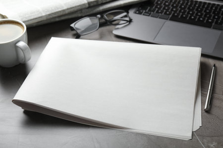 Newspapers, laptop, coffee, pen and glasses on gray table, closeup. Mockup for designの写真素材