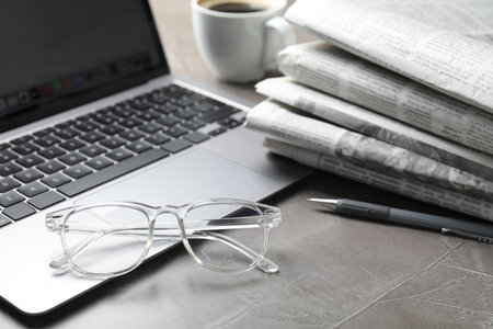 Newspapers, laptop, pen and glasses on gray table, closeupの写真素材
