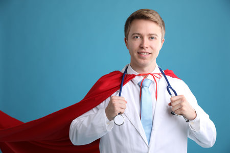 Doctor wearing superhero cape on light blue background. Space for textの写真素材