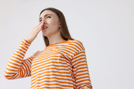 Young woman suffering from smell and covering her nose indoors, low angle view. Space for textの写真素材