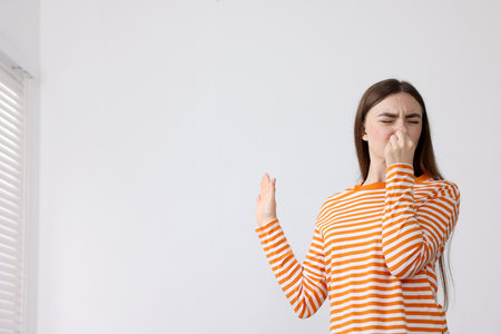 Young woman covering her nose indoors, space for textの写真素材