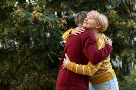 Mother and son hugging outdoors, space for textの写真素材