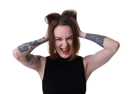 Young woman with piercings, tattoos and stylish clothes posing on white background