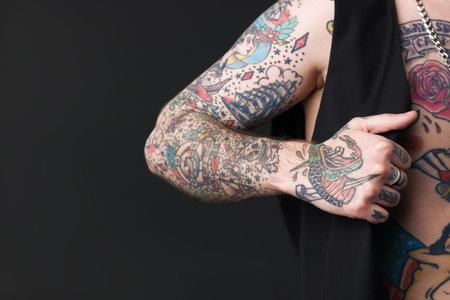 Young man with tattoos and stylish clothes posing on dark gray background, closeup. Space for textの写真素材