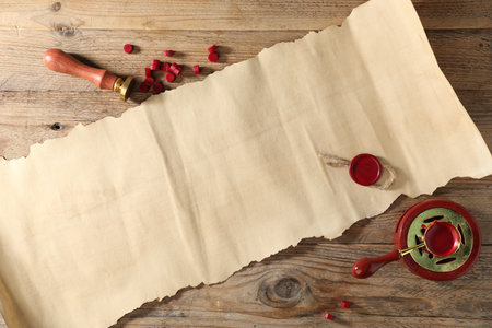 Old paper scroll with wax seal and stamp on wooden table, flat layの写真素材