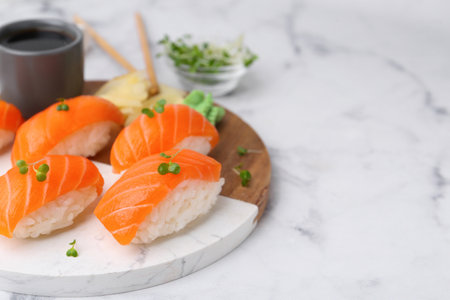 Delicious nigiri sushi with salmon, microgreens, ginger and soy sauce on white marble table, closeup. Space for textの写真素材