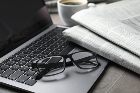 Newspapers, laptop and glasses on gray table, closeupの写真素材