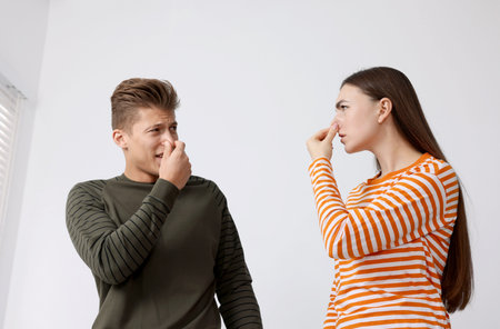 Couple suffering from smell and covering their noses indoorsの写真素材
