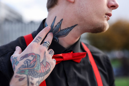 Young man with piercings, tattoos and stylish clothes outdoors, closeupの写真素材