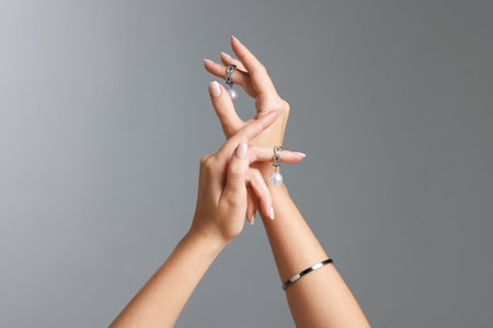 Woman with stylish earrings and bracelet on gray background, closeupの写真素材