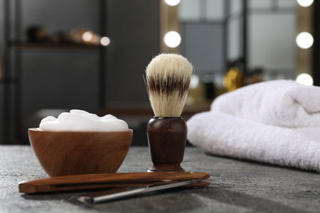Shaving brush, foam and straight razor on gray textured table in barbershop, closeupの写真素材
