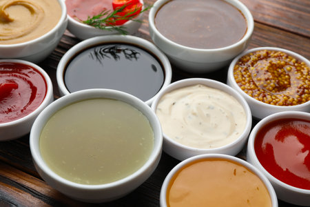 Different sauces in bowls on wooden table, closeupの写真素材
