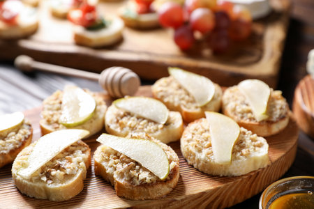 Tasty bruschettas with apples, honey and walnuts on wooden table, closeupの写真素材