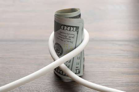 Electrical wire with dollar banknotes on wooden table, closeupの写真素材