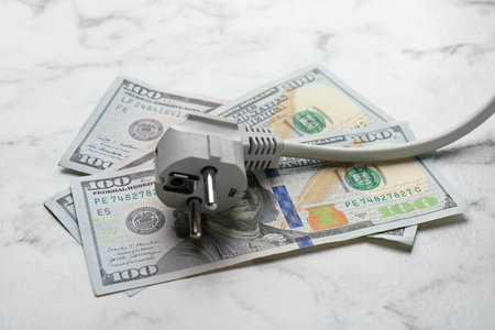 Electrical wire with plug and dollar banknotes on white marble table, closeupの写真素材