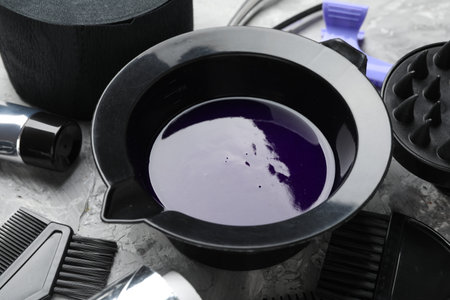 Hair dyeing product in bowl and different hairdresser's tools on light gray table, closeupの写真素材