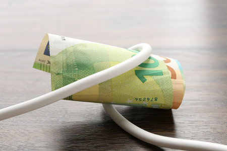 Electrical wire with euro banknotes on wooden table, closeupの写真素材