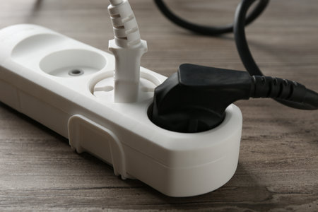 Power strip with electrical plugs on wooden table, closeupの写真素材