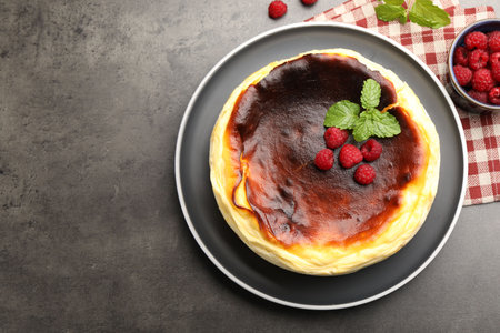 Tasty Basque cheesecake, raspberries and mint on gray textured table, flat lay. Space for textの写真素材