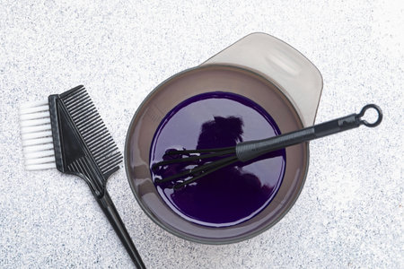 Hair dyeing product in bowl and hairdresser's tools on light gray table, flat layの写真素材