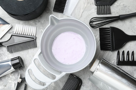 Hair dyeing product in bowl and different hairdresser's tools on light gray table, flat layの写真素材