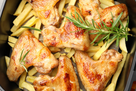 Grilled chicken wings and French fries with rosemary in air fryer basket, closeupの写真素材