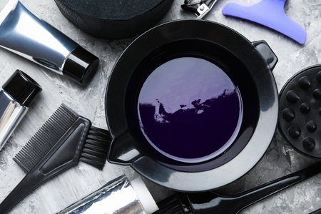 Hair dyeing product in bowl and different hairdresser's tools on light gray table, flat layの写真素材