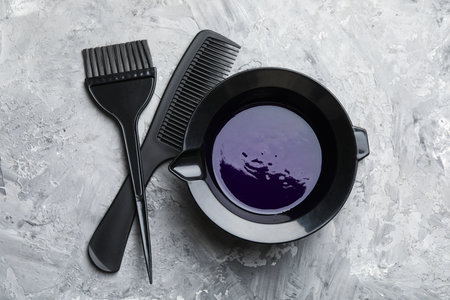 Hair dyeing product in bowl, comb and applicator on light gray table, flat layの写真素材