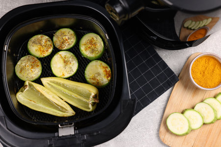 Air fryer basket with vegetables and spices on gray table, flat layの写真素材