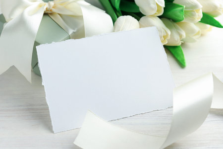 Blank card, gift and flowers on white wooden table, closeup. Mockup for designの写真素材