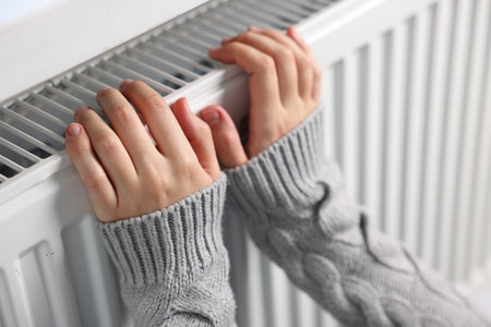 Woman warming her hands near radiator indoors, closeupの写真素材