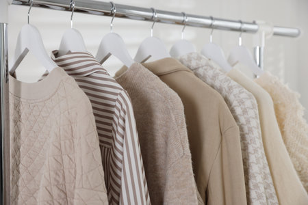 Different stylish clothes hanging on rack indoors, closeupの写真素材