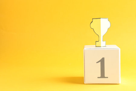 Winner. Paper trophy cup on cube number 1 against orange background, space for textの写真素材
