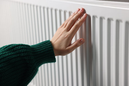 Woman warming her hand near radiator indoors, closeupの写真素材