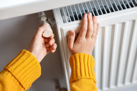 Woman adjusting temperature of radiator indoors, closeupの写真素材