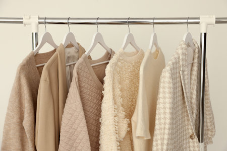 Different clothes hanging on rack against light background, closeupの写真素材