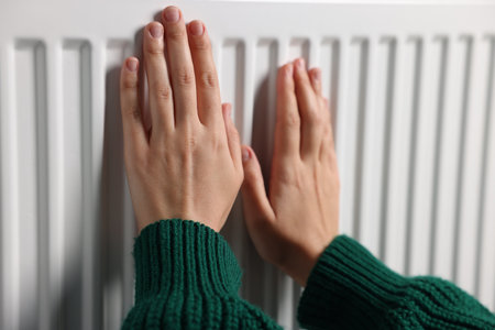 Woman warming her hands near radiator indoors, closeupの写真素材
