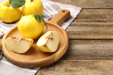 Whole and cut ripe quinces on wooden table, closeup. Space for textの写真素材