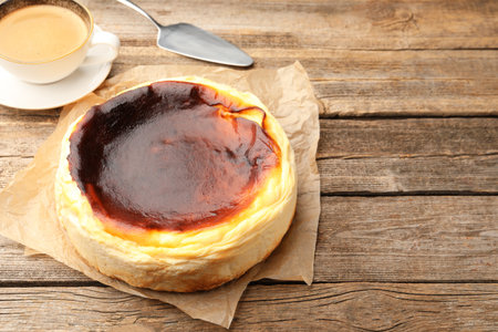 Tasty Basque cheesecake, coffee and spatula on wooden table, closeup. Space for textの写真素材