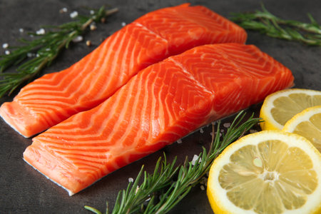 Pieces of salmon fillet and spices on gray table, closeup