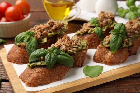 Delicious bruschettas with tuna, avocado and basil on wooden table, closeupの写真素材