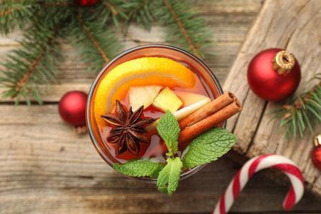 Tasty punch drink in glass, spices and Christmas decor on wooden table, flat layの写真素材