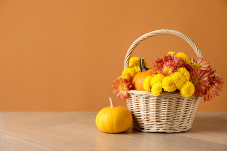 Beautiful autumn composition with flowers and pumpkins on wooden table against orange background. Space for textの写真素材