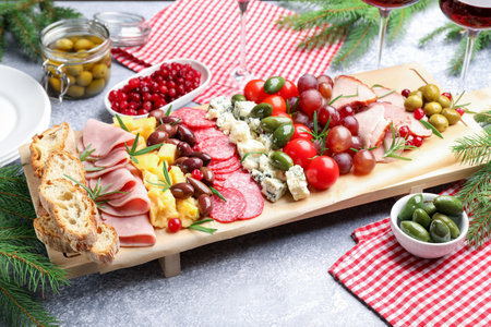 Delicious Christmas Charcuterie board with snacks and fir branches on gray textured table, closeupの写真素材
