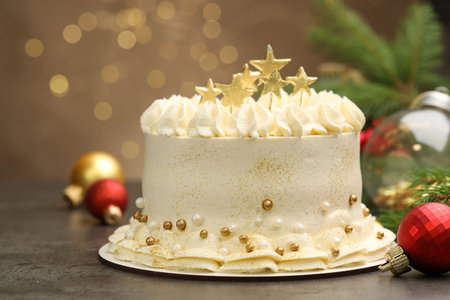 Delicious cake with Christmas decor on gray table against blurred lights, closeup