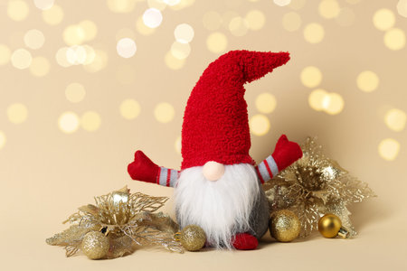 Funny Christmas gnome and festive decor on beige background with blurred lights