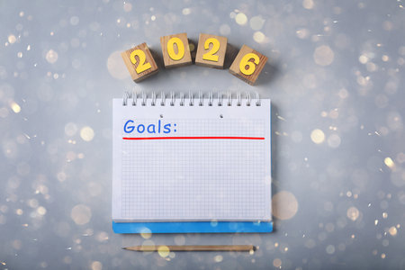 New 2026 Year Goals. Inscription in notebook and cubes with numbers on gray background, top view. Bokeh lightsの写真素材