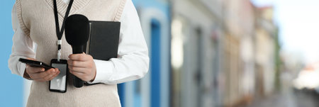Person with microphone, mobile phone and notebook outdoors, closeup.の写真素材