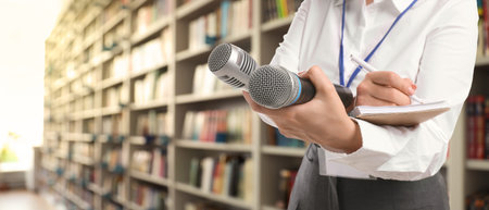 Journalist with microphones writing in notebook near shelves in library, closeup. Banner design